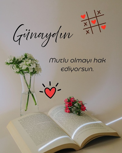 Açık kitap ve beyaz çiçeklerle mutlu olmayı anlatan resimli günaydın mesajı
